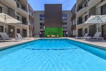 A swimming pool in front of a building with a green wall.